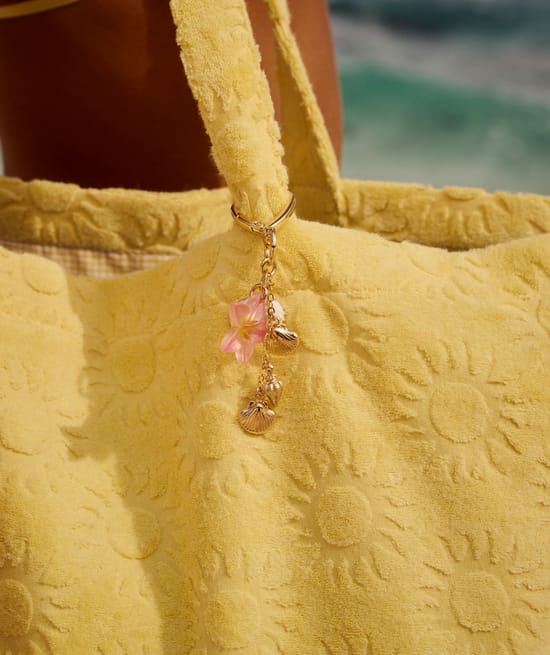 Golden keychain with seashells and hibiscus;