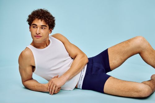 homme allong&eacute; qui porte un boxer bleu marine et un d&eacute;bardeur blanc